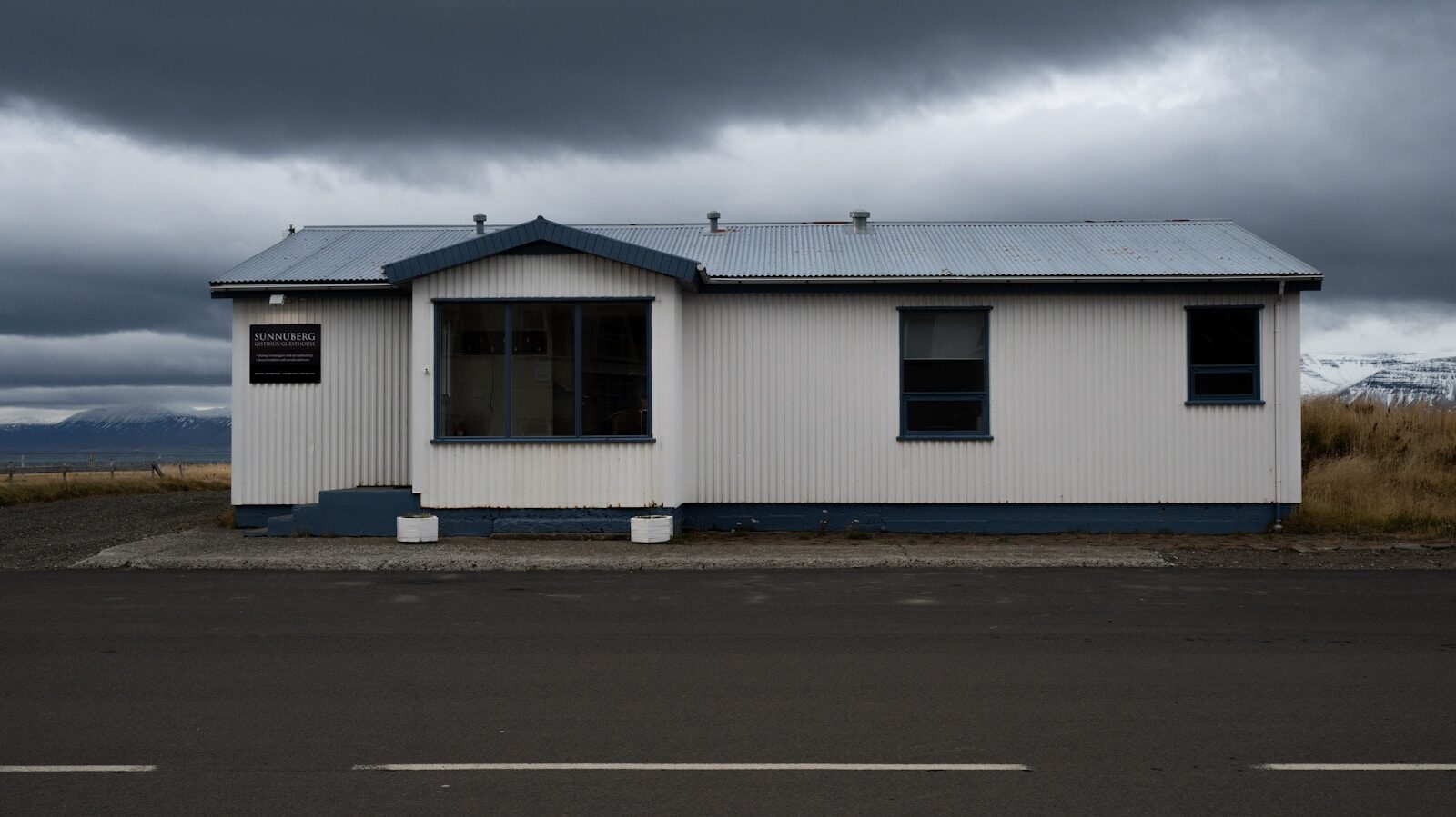 A white house sits under a stormy, grey sky.
